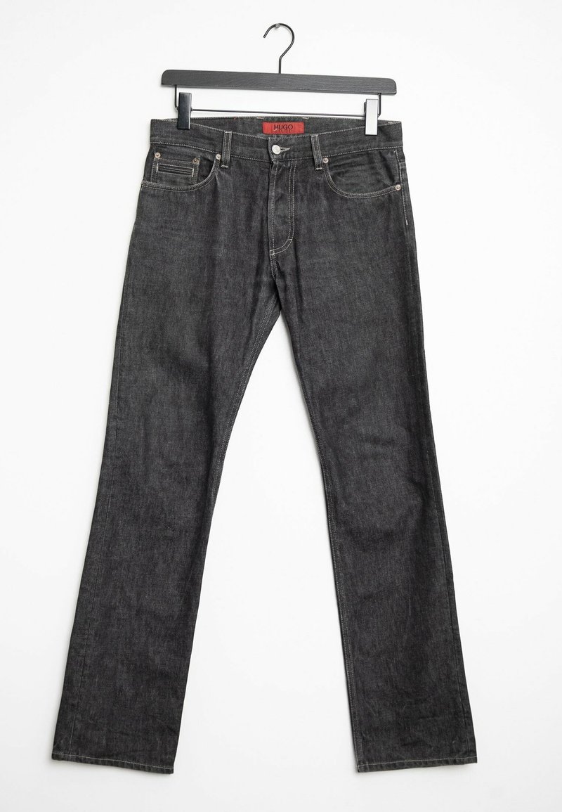Jeans in denim grigio scuro con design a gamba dritta, cinque tasche e cuciture a contrasto, appesi a un gancio in metallo nero.