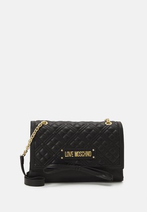 Zwarte gewatteerde handtas met gouden metalen logo-plaatje, kettingriem en strikdetail. Gladde textuur met een rechthoekige vorm en een overslagdesign.