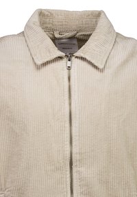 Beige fløjlsjakke med lynlåslukning og krave. Har vertikale ribstriber og et almindeligt pasformdesign.