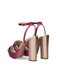 Sandalias de tacón en rosa y dorado con correas entrelazadas, hebilla en el tobillo y tacones de bloque texturizados. Acabado metálico con un aspecto brillante.