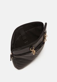 Sort quiltet taske i kunstlæder med lynlås, guldfarvede dekorative elementer og en enkel sort inderside. Har to håndtag øverst.