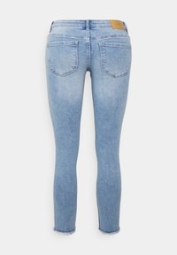 Jeans skinny em denim azul claro com textura desbotada, apresentando dois bolsos traseiros e acabamento desfiado. Pala em pele na cintura.