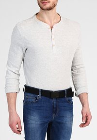 Gray ribbed long-sleeve henley shirt with three buttons. Worn with dark blue jeans and a black belt. Focus on texture and contrasting colors.
