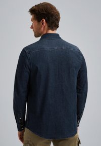 Granatowa koszula z denimu z kołnierzykiem, długimi rękawami i zapinanymi mankietami. Posiada zaokrąglony dół oraz subtelne detale przeszycia.