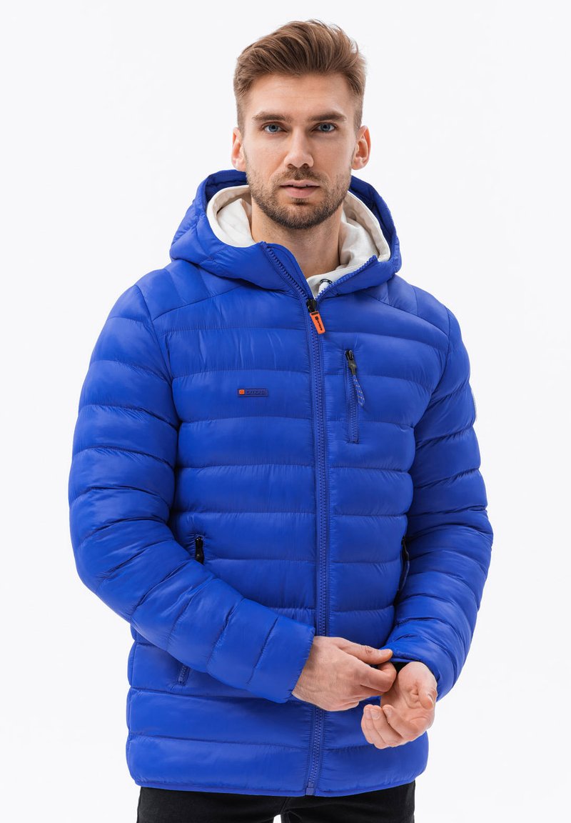 Giacca puffer blu con cappuccio, caratterizzata da sezioni a costine orizzontali, chiusura frontale con zip e due tasche laterali, realizzata in un materiale lucido.