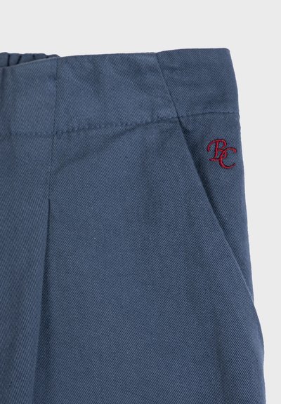 Niebieskie spodnie dżinsowe z elastycznym paskiem w talii oraz małym czerwonym haftowanym logo "PC" blisko kieszeni po prawej stronie.