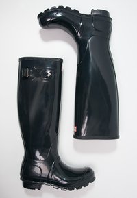 Botas de lluvia de goma negras con acabado brillante, detalle de hebilla ajustable, suelas resistentes y un diseño hasta la rodilla para protección contra el clima.