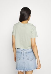 Ljusgrön kortärmad t-shirt i bomull, kombinerad med en fransig denimminikjol med bakfickor och hög midja.