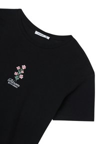 T-shirt in cotone nero con maniche corte, scollatura rotonda e ricamo floreale rosa con il testo "Fiorisci con Grazia."