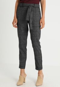Grå rutiga byxor med ett tygbälte, tapered ben-design, midja i normalhöjd och slät textur. Bärs med beige klackmules.