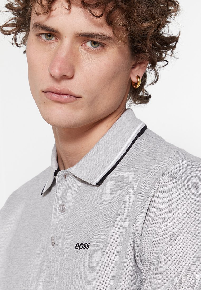 Grijze polo met een textuurstof, voorzien van een zwart-wit gestreepte kraag en een klein "BOSS" logo op de borst.