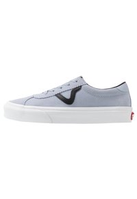 Zapatilla de ante gris claro con acentos negros, suela de goma blanca y costuras contrastantes; diseño de cordones, perfil bajo y logo en el talón.