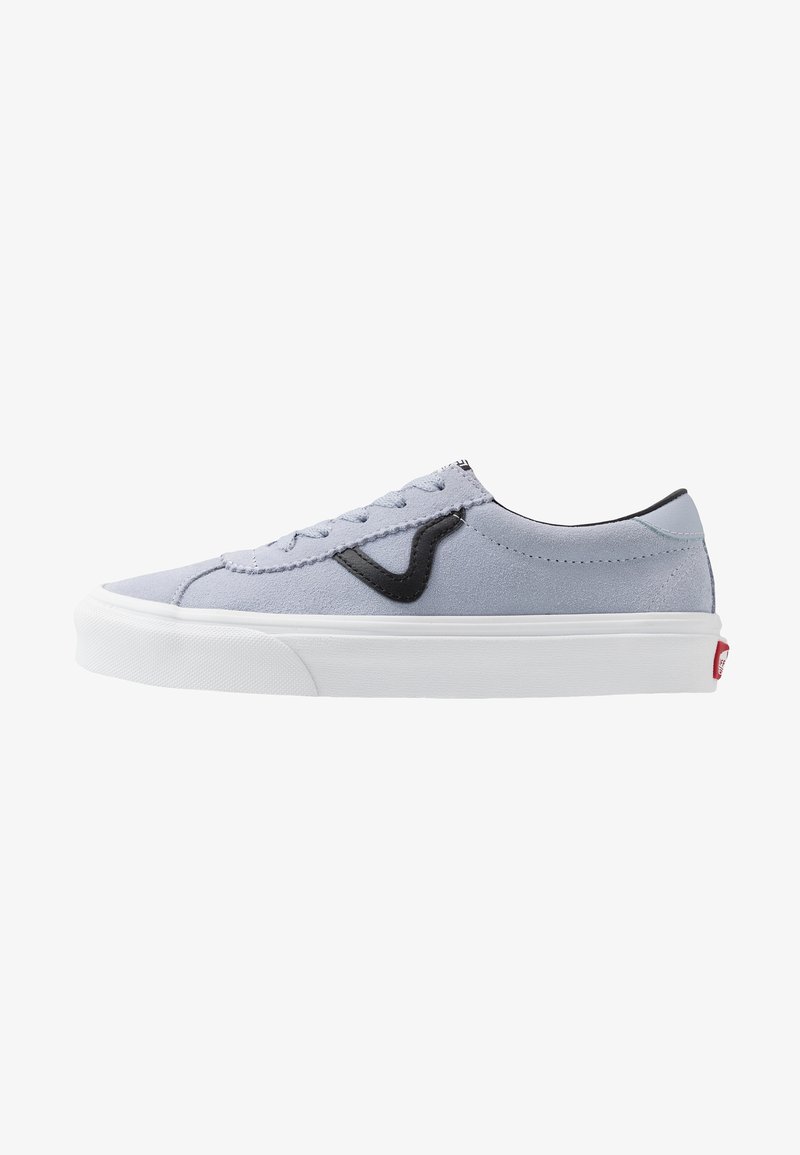 Zapatilla de ante gris claro con acentos negros, suela de goma blanca y costuras contrastantes; diseño de cordones, perfil bajo y logo en el talón.