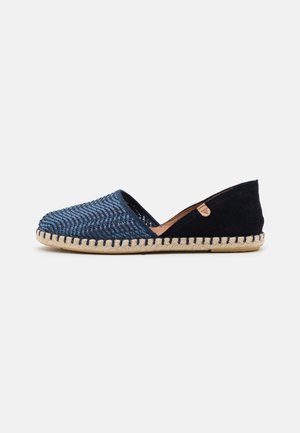 Codzienne, płaskie buty wsuwane z tkanym niebieskim przodem, czarnym zamszowym piętą, beżową przeszywaną podeszwą i małą skórzaną metką marki po boku.
