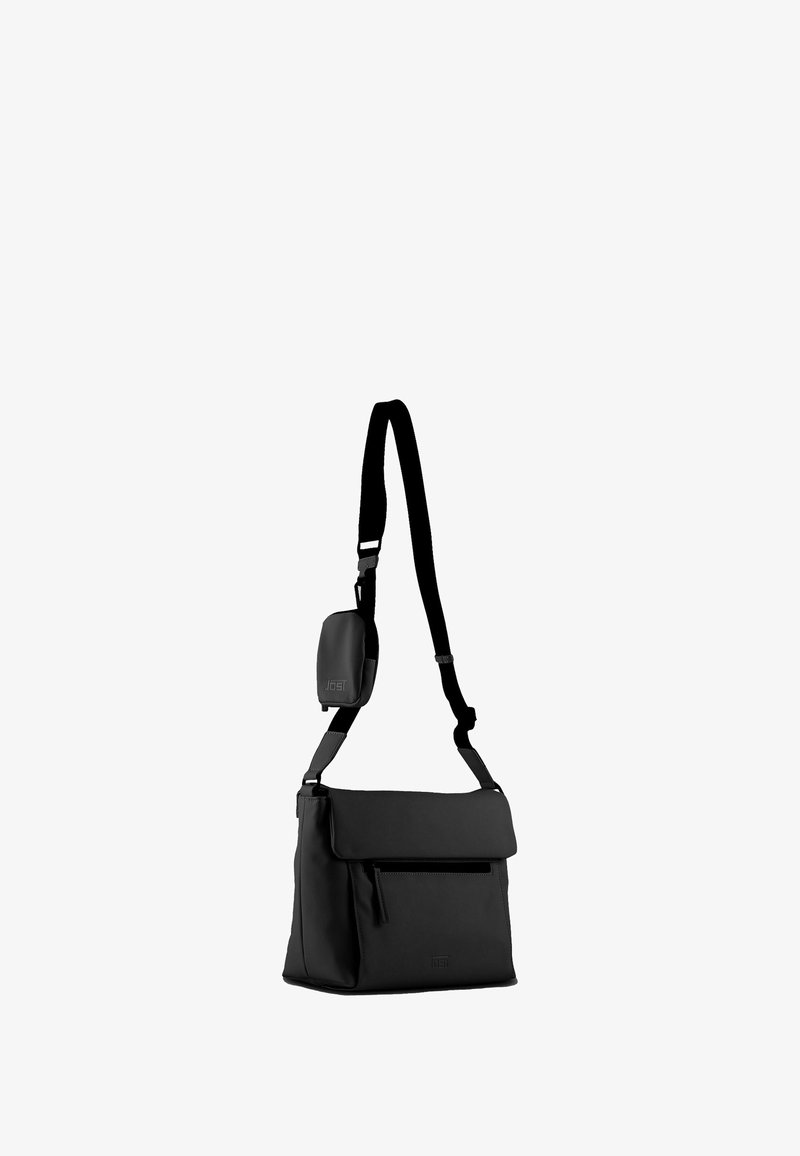 Borsa a tracolla nera in materiale sintetico con chiusura a pattina, tracolla regolabile, tasca frontale con zip e texture liscia. Presenta un dettaglio del logo sulla parte anteriore.