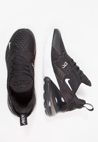 Black athletic shoes with mesh upper, rounded toe, and air cushioning in the heel. White accents on the sides and heel tab.