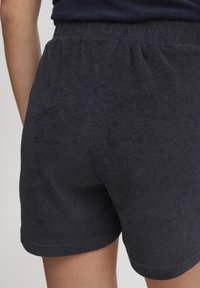 Marinblå frottéshorts med elastisk midje og oppbrettede kanter, som har en myk tekstur og enkel design.