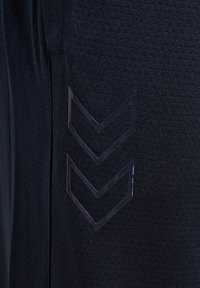 Marine sportbroek van een gestructureerde stof, met een elastische tailleband en plastic chevronaccenten aan de zijkant voor extra detail.