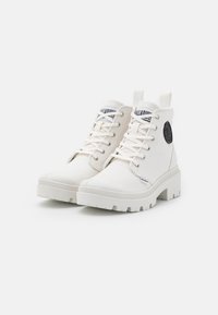 Botas altas blancas de lona con una suela texturizada, que presentan cordones planos, una lengüeta y un acento de logo redondo en el lateral.