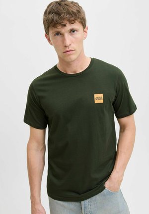 Mørkegrøn bomulds t-shirt med rund halsudskæring, korte ærmer og et lille firkantet orange logo på venstre bryst. Casual pasform.