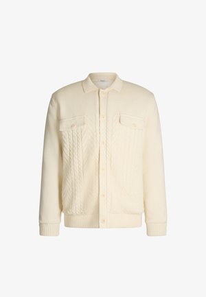 Gebreide crèmekleurige jas met een kraag en twee borstzakken; beschikt over kabelgebreide patronen aan de voorkant, geribbelde manchetten en zoom.