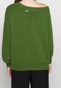 Overgrote groene gebreide trui met een wijde halslijn, lange mouwen en een textuurafwerking, met een klein metallic logo-detail op de achterkant.