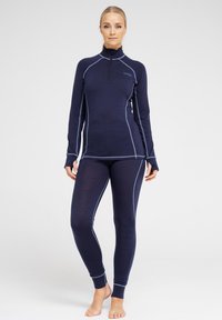 Meri setti aktiivista alusvaatetta laivastonsinisestä väristä, jossa on pitkähihainen paita, jossa on puolivetoketju, ja tiukat leggingsit. Kontrastivärinen ompelu tuo lisäyksityiskohtia.