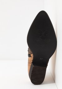 Brown leather shoe with embossed scales, pointed toe, black inset heel, and subtle branding on the sole, size marked as 37.