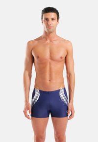 Ανδρικό σορτς κολύμβησης σε ναυτικό μπλε χρώμα από απαλό ύφασμα, με λευκές γεωμετρικές πλαϊνές πάνελ, εφαρμοστό σχέδιο και μέση μεσαίου ύψους.