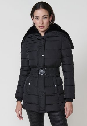 Abrigo acolchado negro con capucha de piel sintética detachable, cintura ceñida con cinturón y cierres de botones. Presenta costuras verticales y bolsillos laterales.