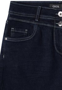 Jean en denim bleu foncé avec des coutures blanches contrastantes, une petite poche à monnaie, des passants de ceinture et deux boutons métalliques gravés du nom de la marque.