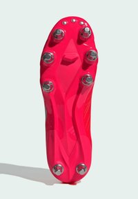 Botas de fútbol rojas con un acabado brillante, que cuentan con ocho clavos de metal, una forma aerodinámica y paneles laterales texturizados para agarre y rendimiento.