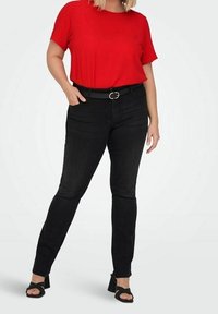 Top corto rojo de manga corta combinado con jeans negros y un cinturón negro con hebilla redonda. Llevado con sandalias de tacón negras.