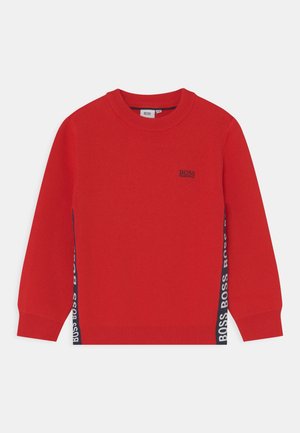Czerwony sweter z długim rękawem i okrągłym dekoltem, z prążkowanymi mankietami i dołem, z czarnym logo "BOSS" na piersi oraz pionowymi logo po bokach.