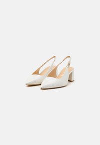 Scarpe slingback bianche con punta affusolata, materiale in finta pelle di coccodrillo testurizzato e tacco chunk. Presentano una cinturino regolabile con fibbia.