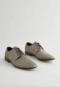 Schnürschuhe aus glitzerndem grauem Material mit spitz zulaufendem Design und schwarzen Absatzakzenten. Glatte Textur mit minimalen Nähten.