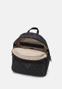 Sac à dos en faux cuir noir avec fermeture zippée, comportant une poche intérieure et une doublure en tissu beige avec un motif de logo répétitif.