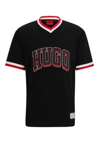 Svart bomullströja med v-ringning och kontrasterande röd och vit randig kant. Har stora texturerade bokstäver "HUGO" framtill.