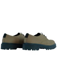 Braune Lederschuhe mit schwarzen Gummisohlen, die eine abgerundete Zehenform und einen niedrigen Absatz besitzen. Schnürdesign mit minimalen Details.