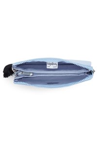 Portafoglio Kipling azzurro chiaro con chiusura a zip, texture in tessuto e un accento di pom-pom nero. L'interno presenta due scomparti e uno slot per carte.