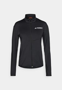 Fekete Terrex dzseki hosszú ujjakkal, magas gallérral, teljes elülső cipzárral és fehér logóval. Könnyű, sima anyagból készült, testhezálló kialakítással.