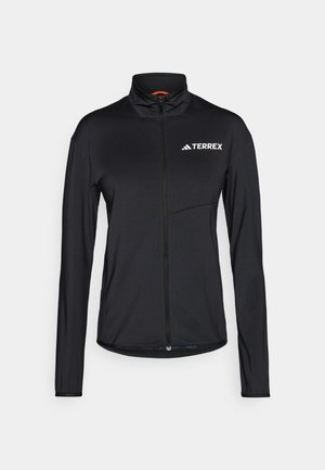 Čierna bunda Terrex s dlhými rukávmi, vysokým golierom, celopredným zipsom a bielym logom. Vyrobená z ľahkej, hladkej tkaniny s priliehavým strihom.