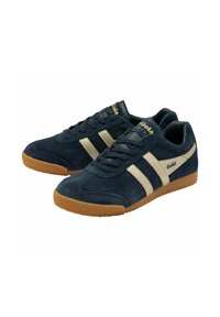 Sneakers in suede blu navy con strisce e logo dorati, dotati di una suola in gomma testurizzata e lacci neri piatti. Design classico e retro.