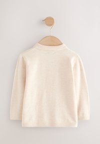 Maglia a maniche lunghe color beige chiaro con collo classico, trama sottile e orlo a coste, esposta su una gruccia di legno su uno sfondo chiaro.