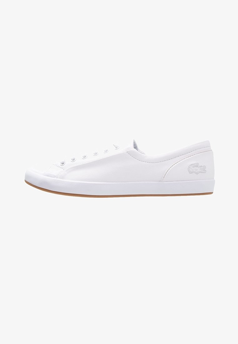 Hvide canvas sneakers med rund tå, snørebånd foran og diskret Lacoste-logo på siden. Gummisål og minimalistisk design.