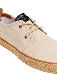 Chaussure décontractée en toile beige avec semelle en jute tressée, devant à lacets et étiquette noire portant l'inscription « Pepe Jeans London Since 1973 » sur la languette.
