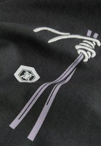 Čierna textília s grafickým motívom štýlizovaných rezancov v bielej a levanduľovej farbe, s hexagonálnym logom v ľavom dolnom rohu.