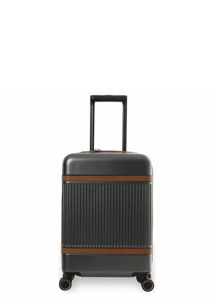 Kova kuorinen musta matkalaukku pystysuuntaisilla uurteilla, ruskeilla reunoilla, vedetty teleskooppikahva ja neljä 360 asteen pyörivää pyörää.