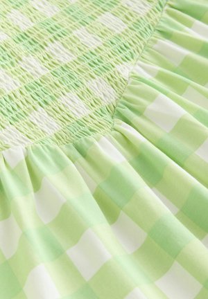 Rochie verde în carouri, cu corpiș smock și textură adunată, completată de o fustă evazată și plisată. Confecționată din bumbac ușor.