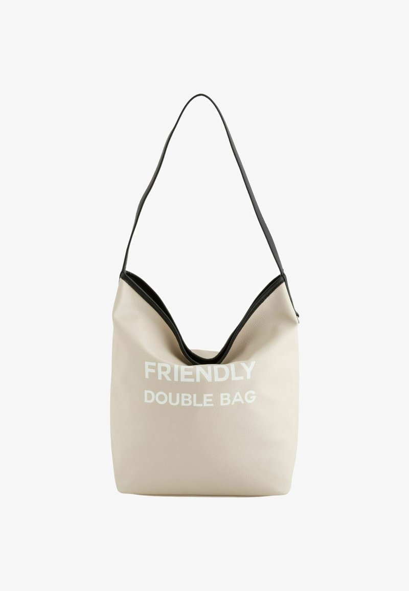 Beige hobo tas gemaakt van gestructureerd materiaal met een zwarte accent, met de tekst "FRIENDLY DOUBLE BAG" in het wit. Zachte, slungelige ontwerp.